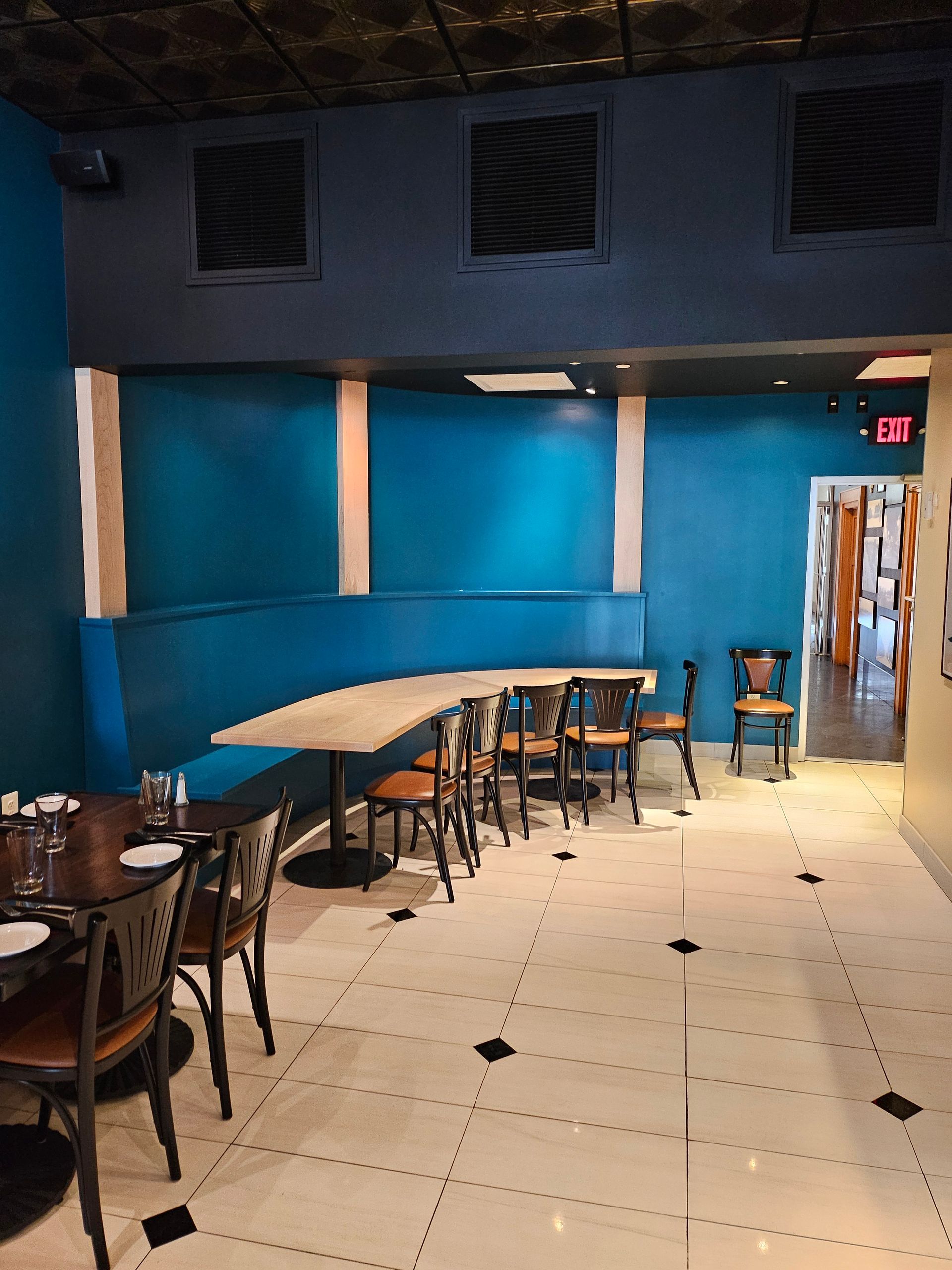 Interior restaurant scene: blue booth seating, tables with chairs, and tiled floor.