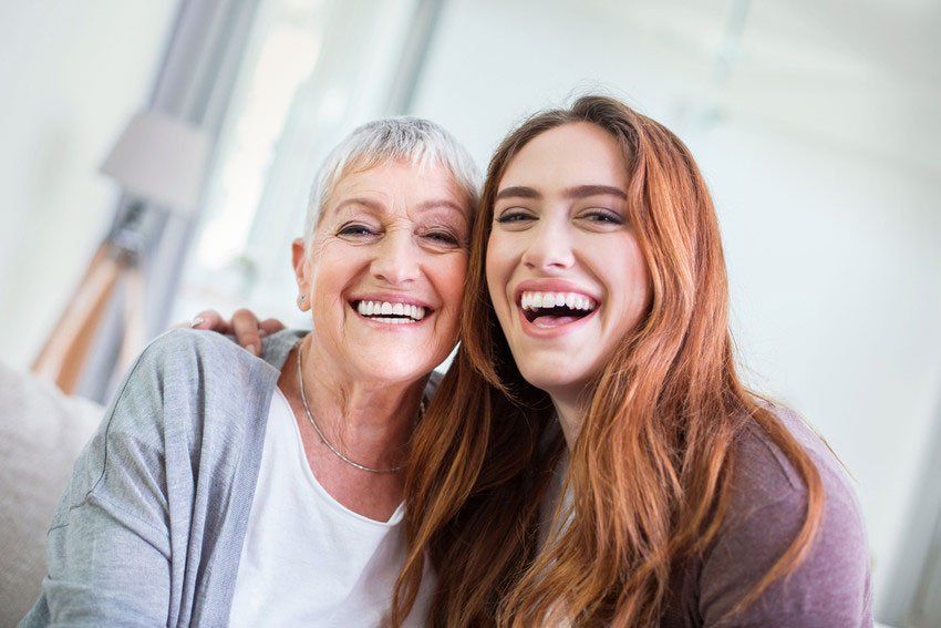 A female care assistant with her arm around an elderly woman as they chat