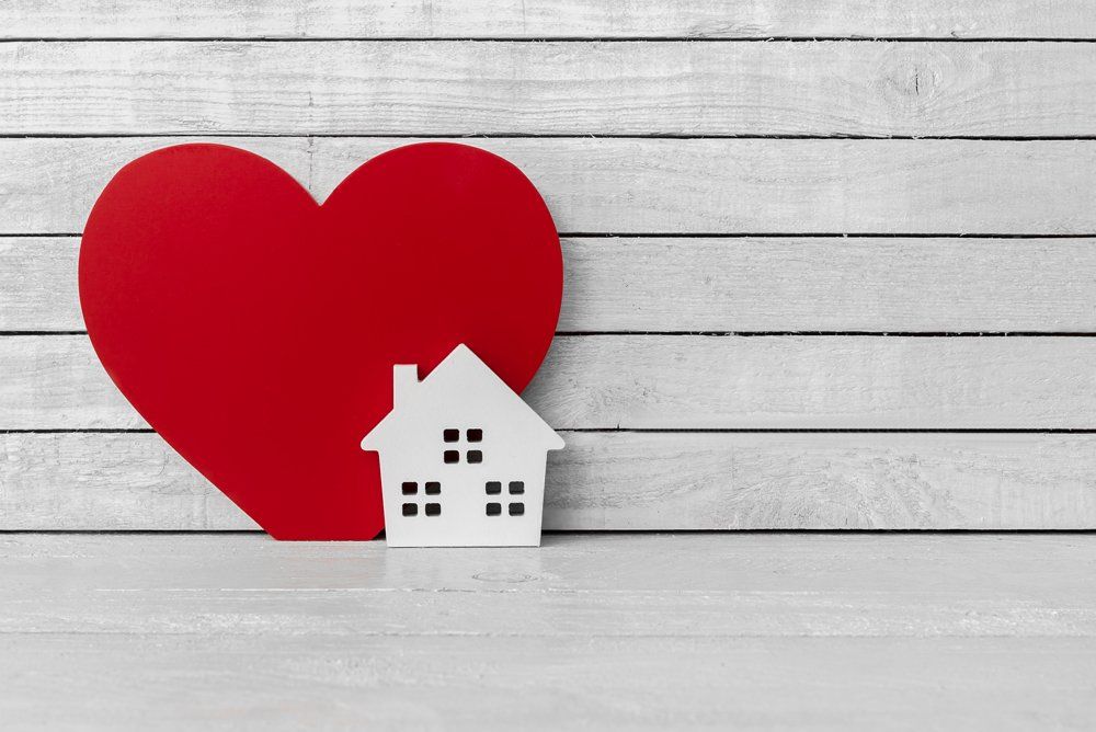 house cut out with a heart against a wood background