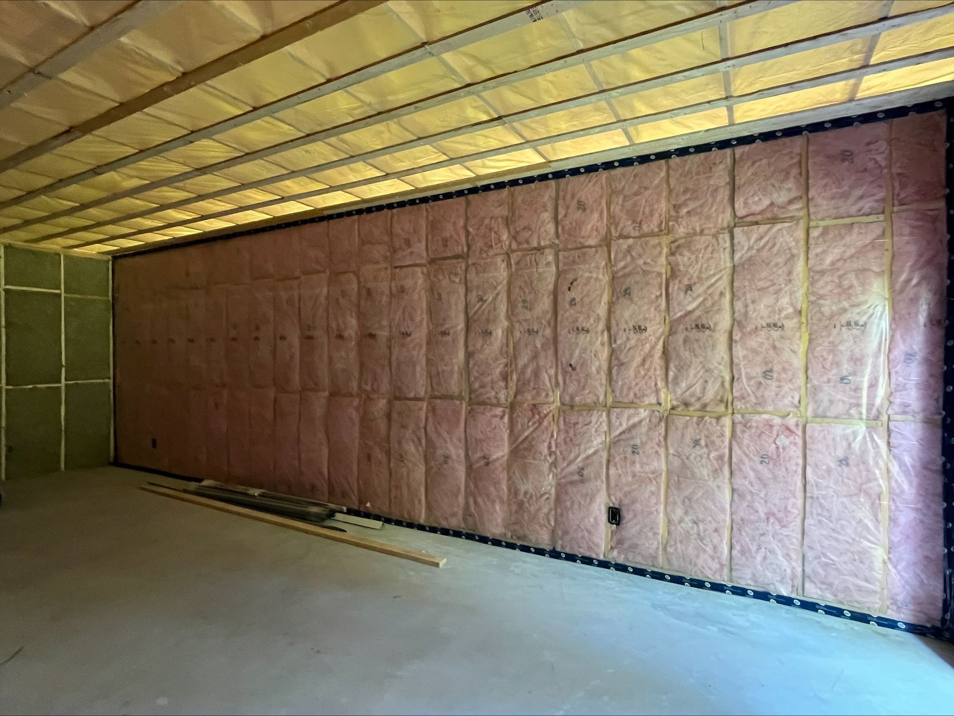 Interior view of a room with pink insulation installed on walls and ceiling.