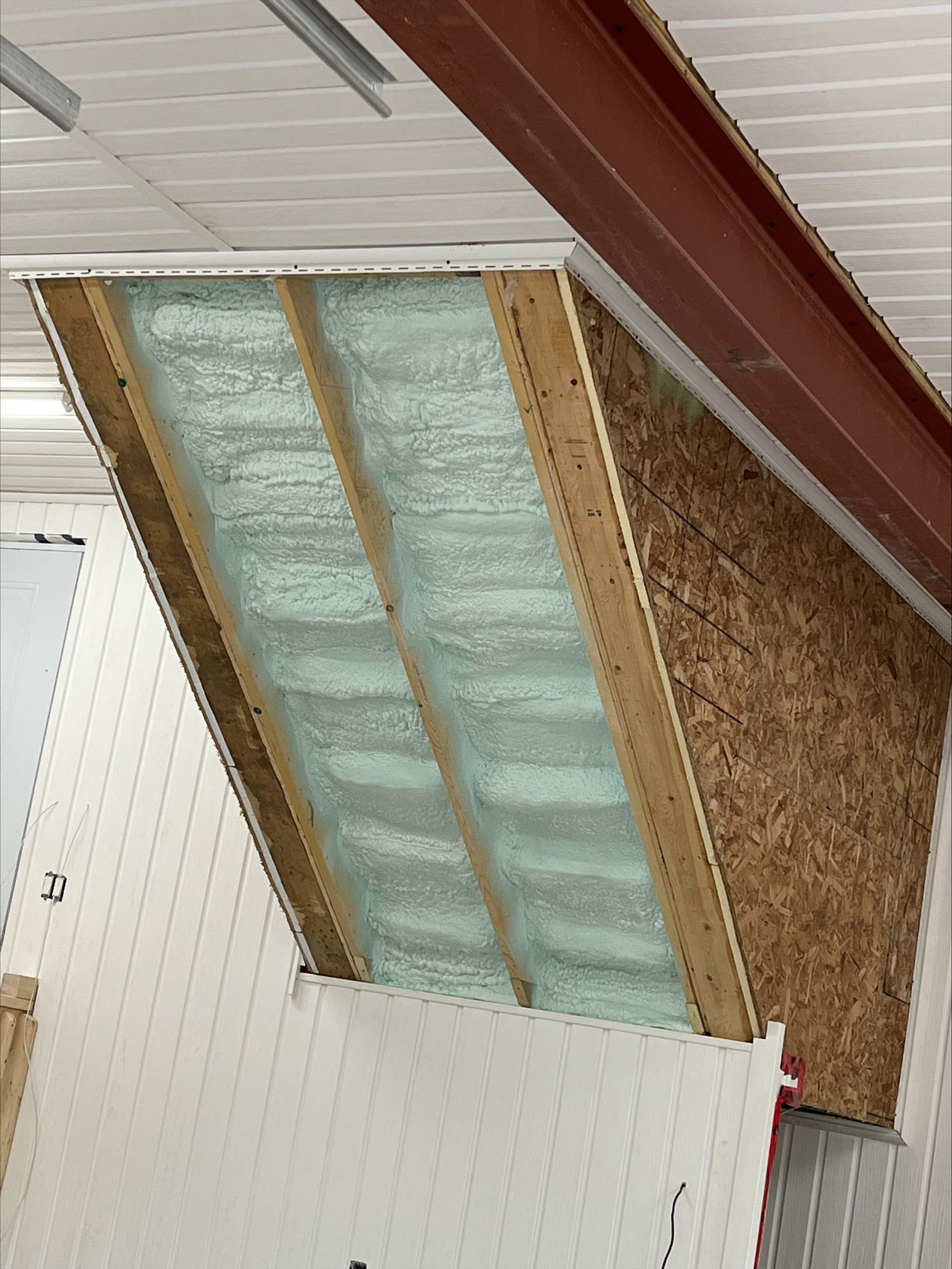 Angled ceiling section with wooden frame, OSB, and foam insulation.