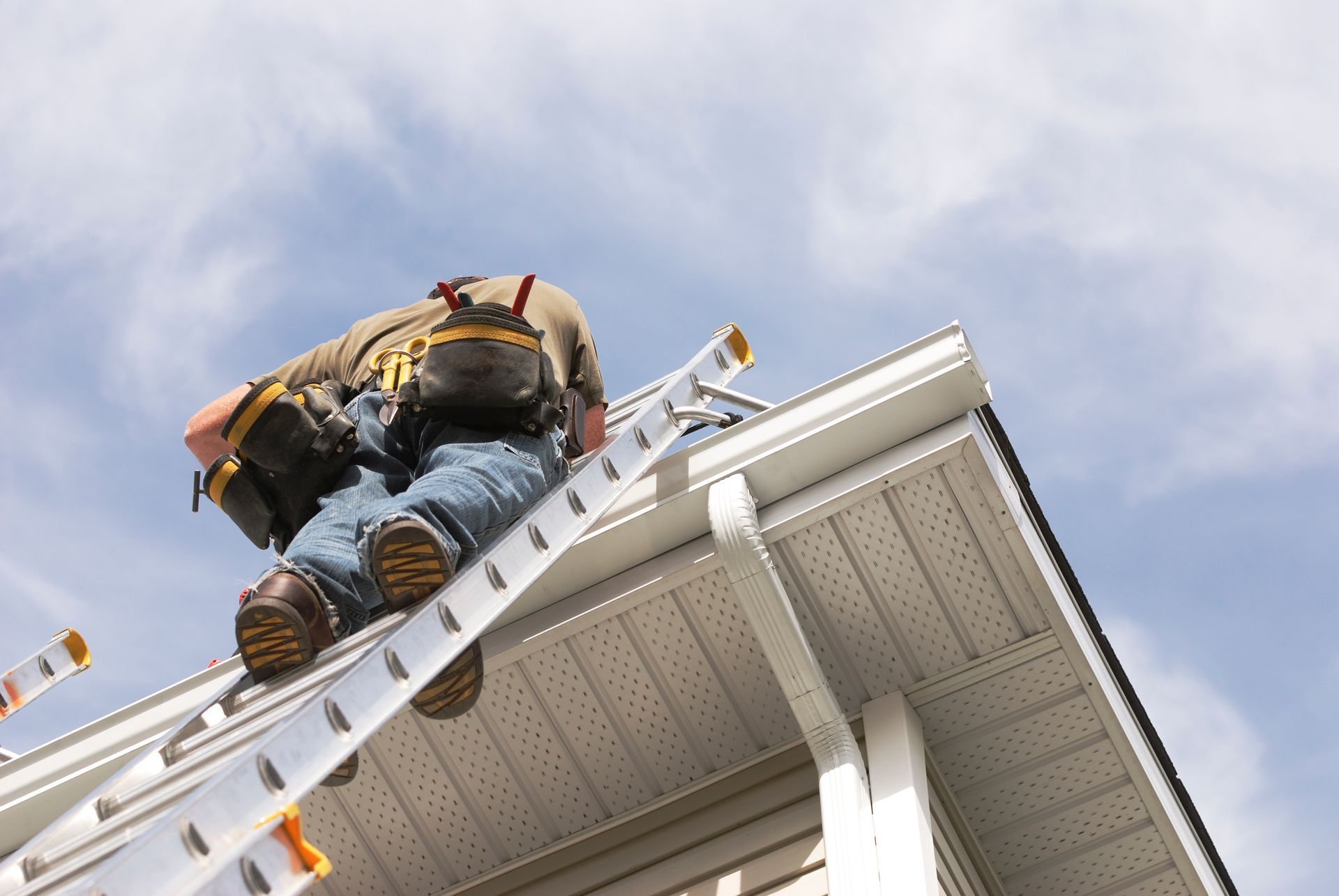 Handyman on ladder performing roof repairs in Pearland, TX, fixing shingles to prevent leaks and ext