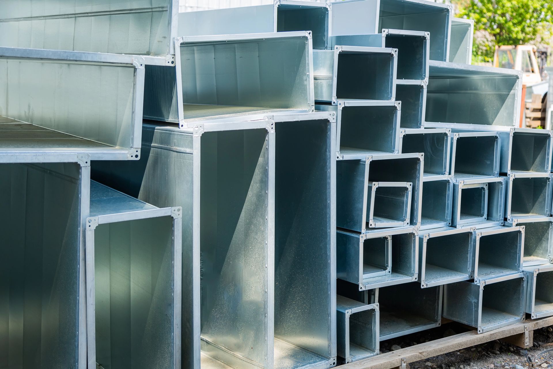 Un montón de tubos de metal se apilan uno encima del otro sobre una paleta de madera.