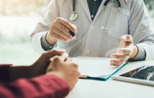 A doctor is talking to a patient while sitting at a table.