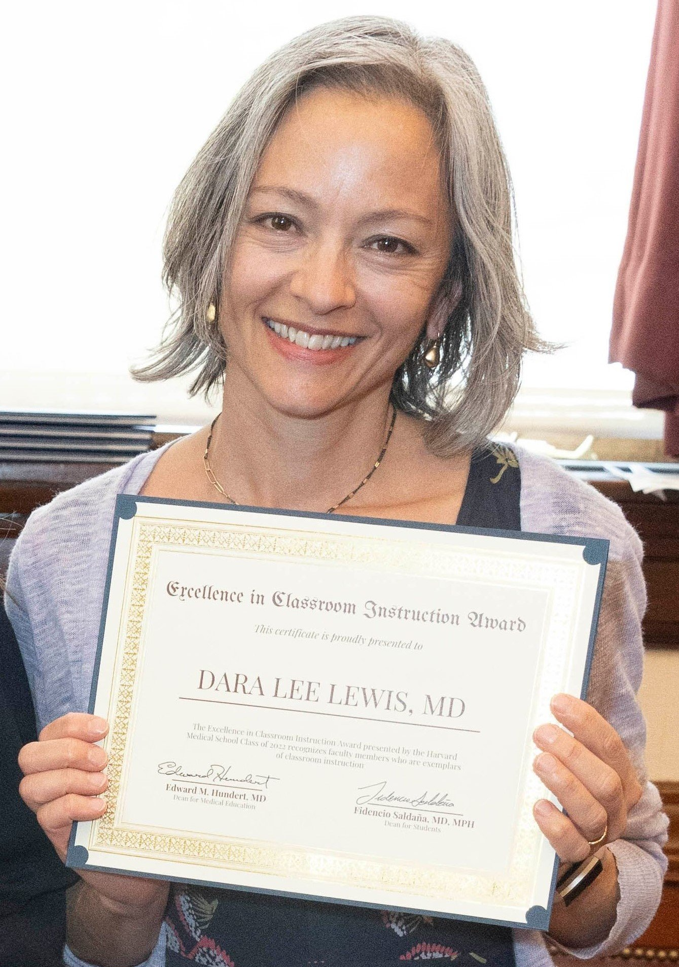 A woman is holding a certificate in her hands and smiling.