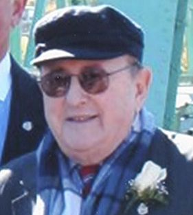 A man wearing a hat and sunglasses is standing next to another man.