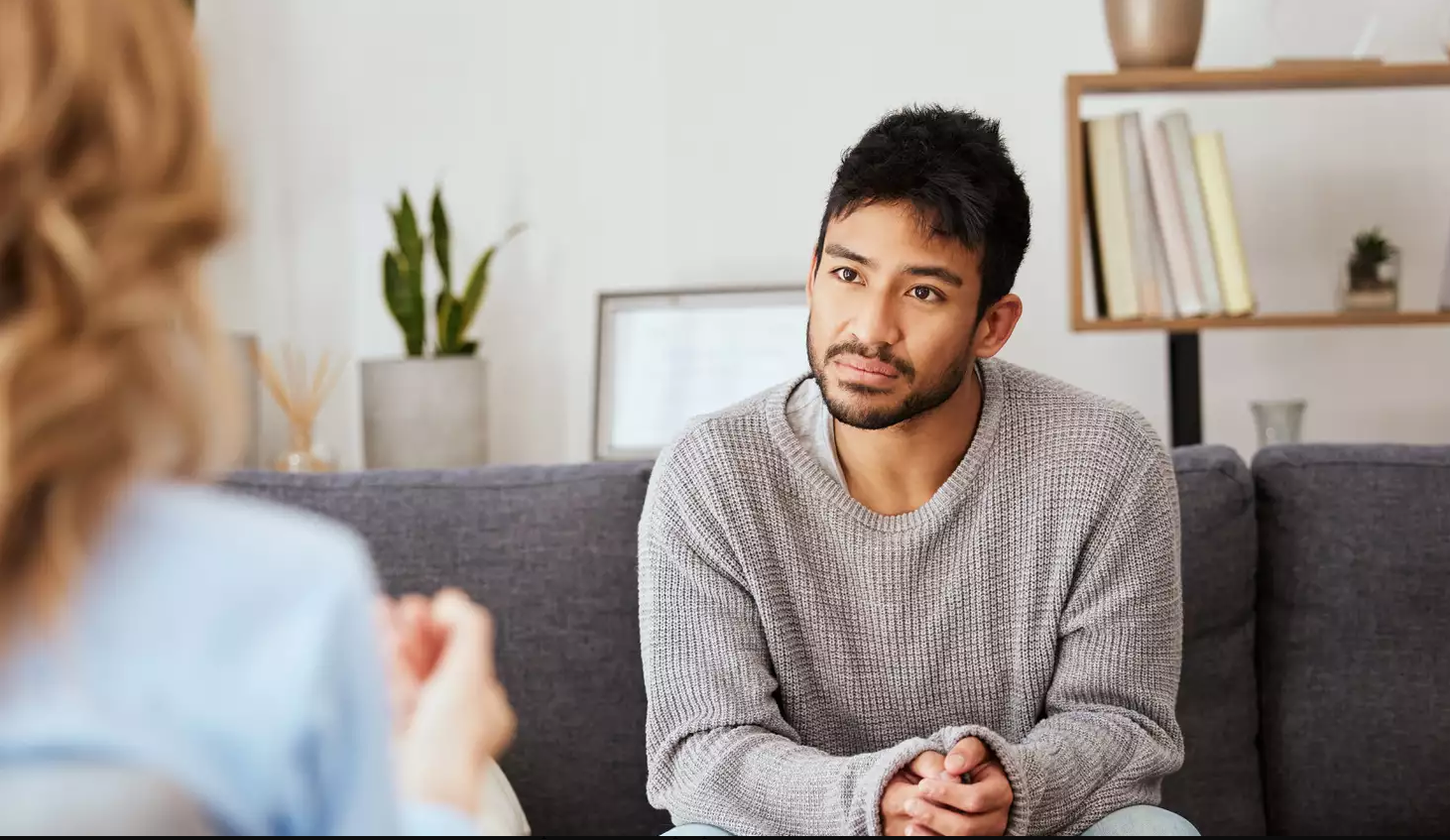 A man is sitting on a couch talking to a woman.