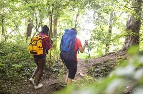 A man and a woman are hiking through the woods.