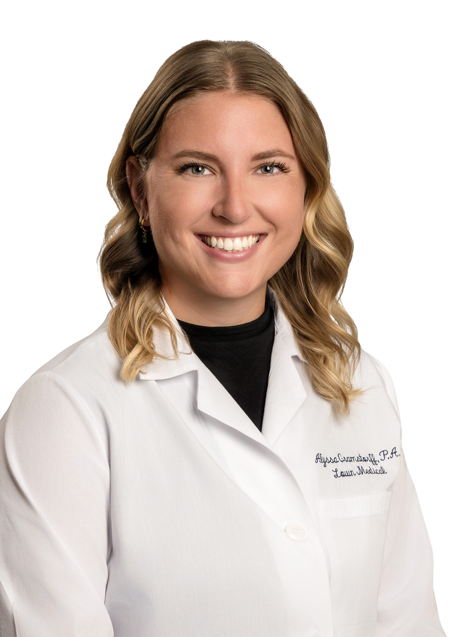 Woman in a lab coat smiles, with wavy blonde hair.
