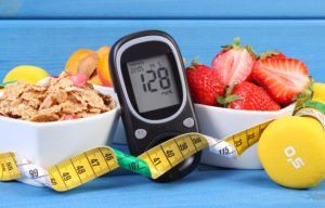 A blood sugar monitor in between two bowls of fruit
