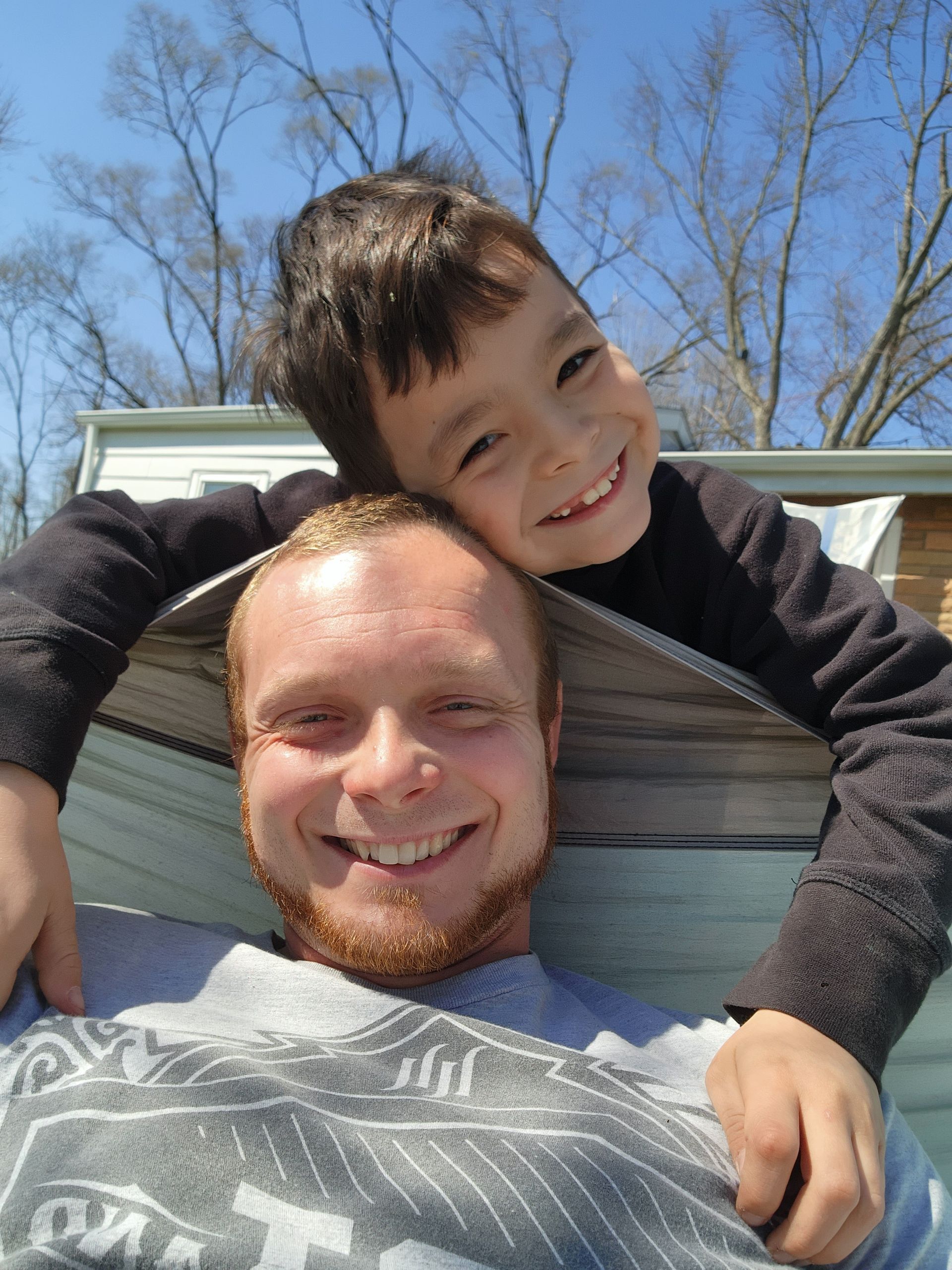 A man is kneeling down and rolling a roll of turf in a garden.