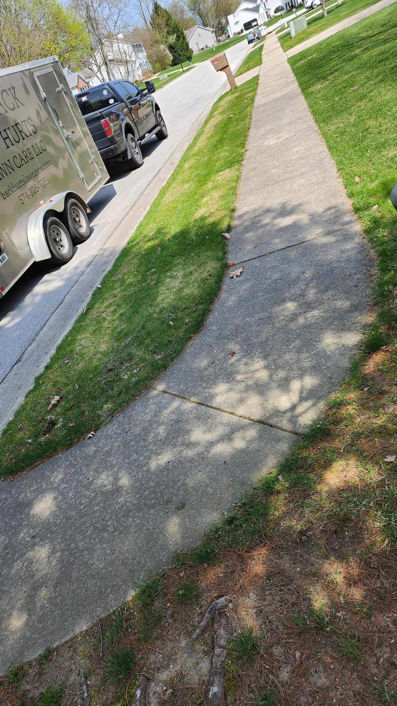 A trailer is parked on the side of the road next to a sidewalk.