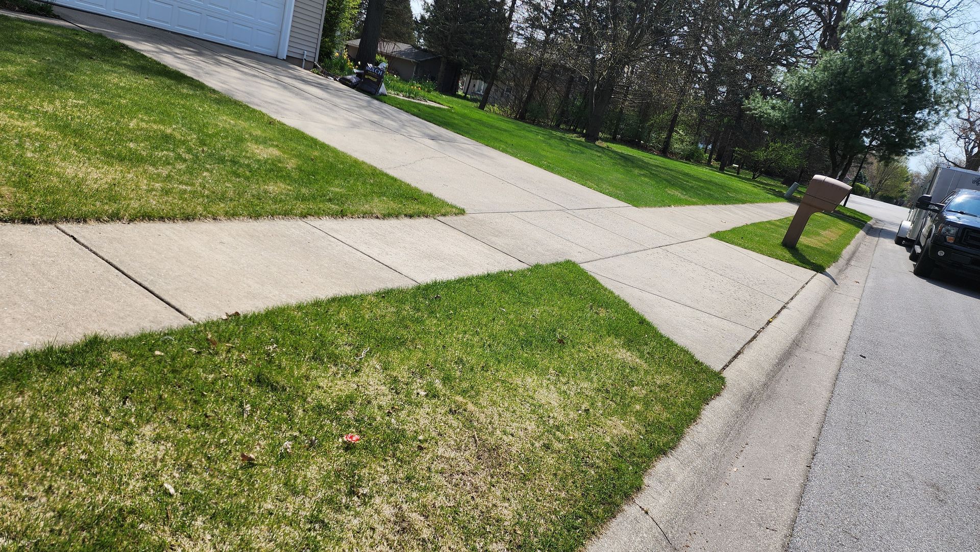 A car is parked on the side of the road next to a lush green lawn.