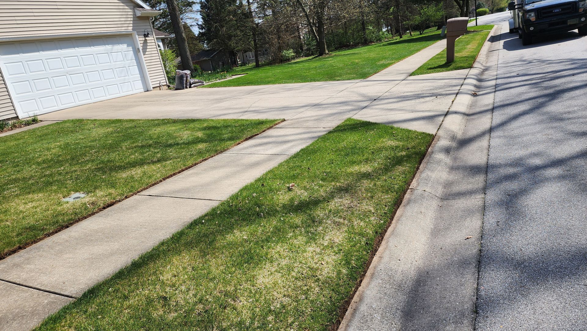 A sidewalk leading to a house with a lush green lawn.