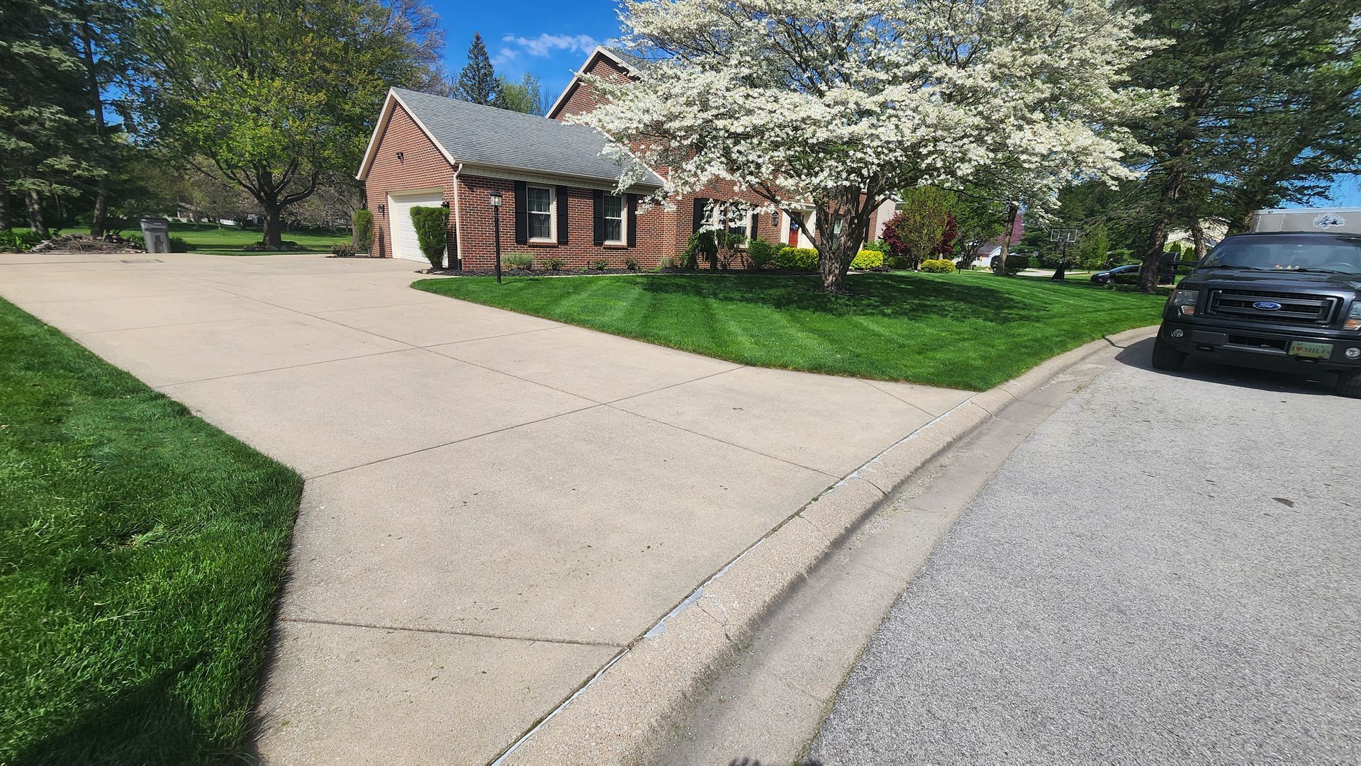 A black truck is parked in front of a brick house.