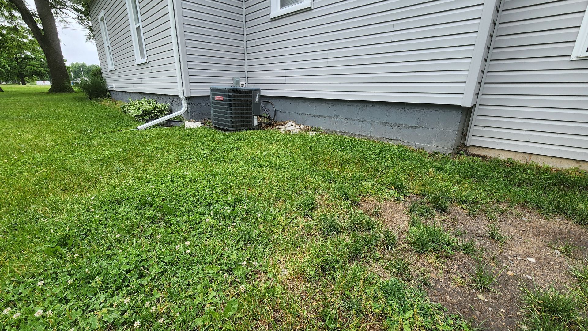 A white house with a black air conditioner on the side of it.