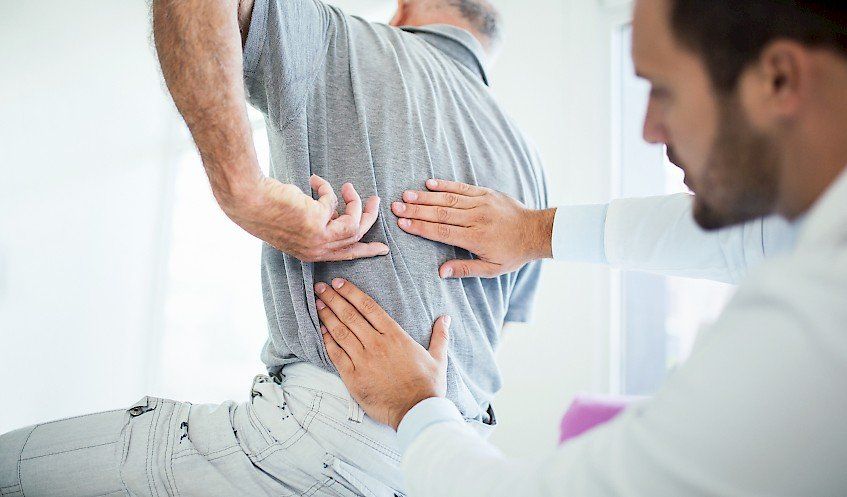 Man With Back Pain Showing Spot of Pain to Doctor 