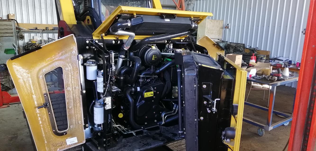 A Yellow and Black Tractor is Being Repaired in a Garage — Giger Machinery Services in Bentley Park, QLD