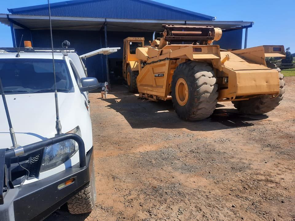 A White Truck is Parked Next to a Large Yellow Truck — Giger Machinery Services in Bentley Park, QLD