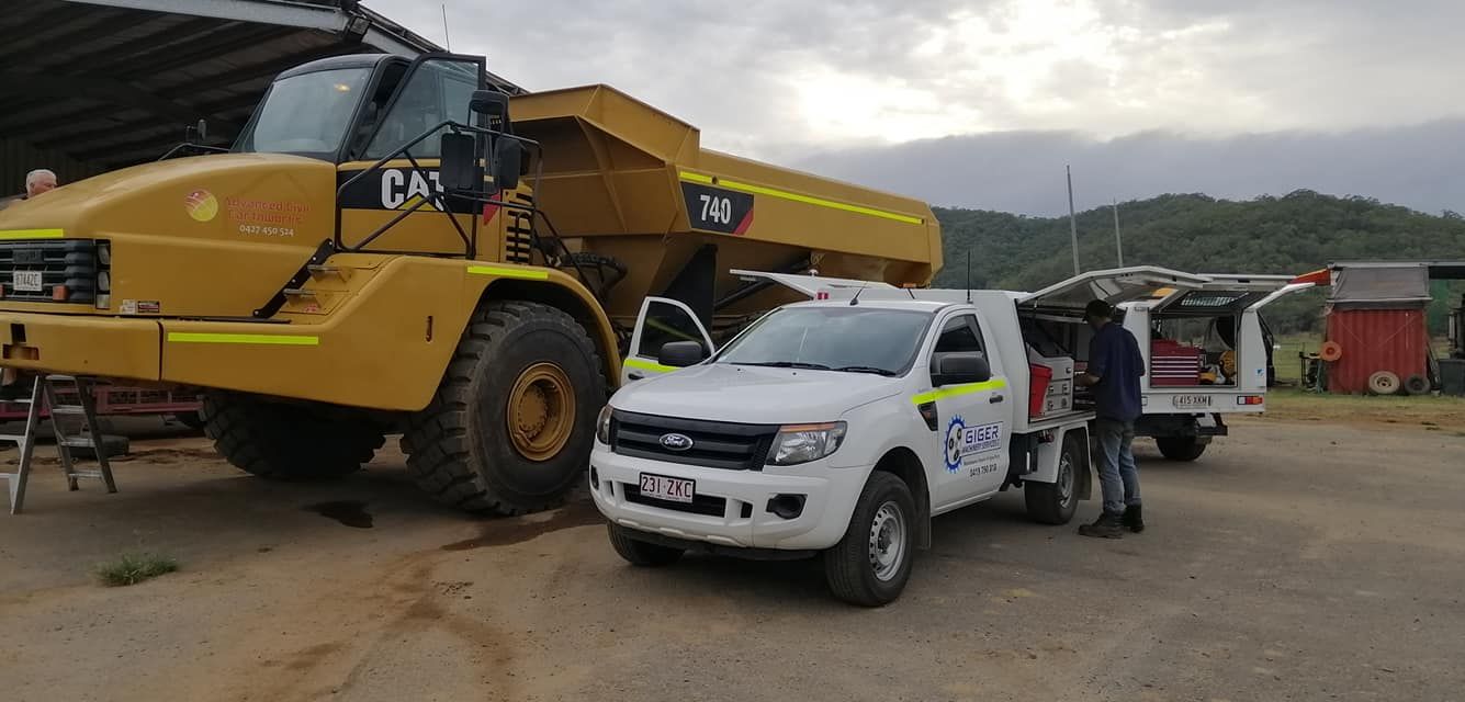 A White Truck is Parked Next to a Large Yellow Dump Truck — Giger Machinery Services in Gordonvale, QLD