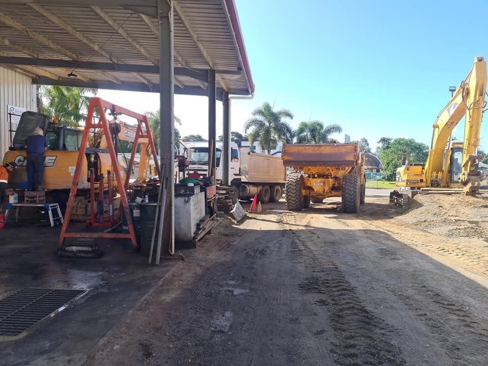 A Large Yellow Dump Truck is Parked in Front of a Building — Giger Machinery Services in Gordonvale, QLD