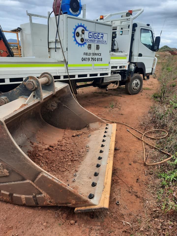 A Truck With a Bucket Attached to It is Parked on a Dirt Road — Giger Machinery Services in Gordonvale, QLD