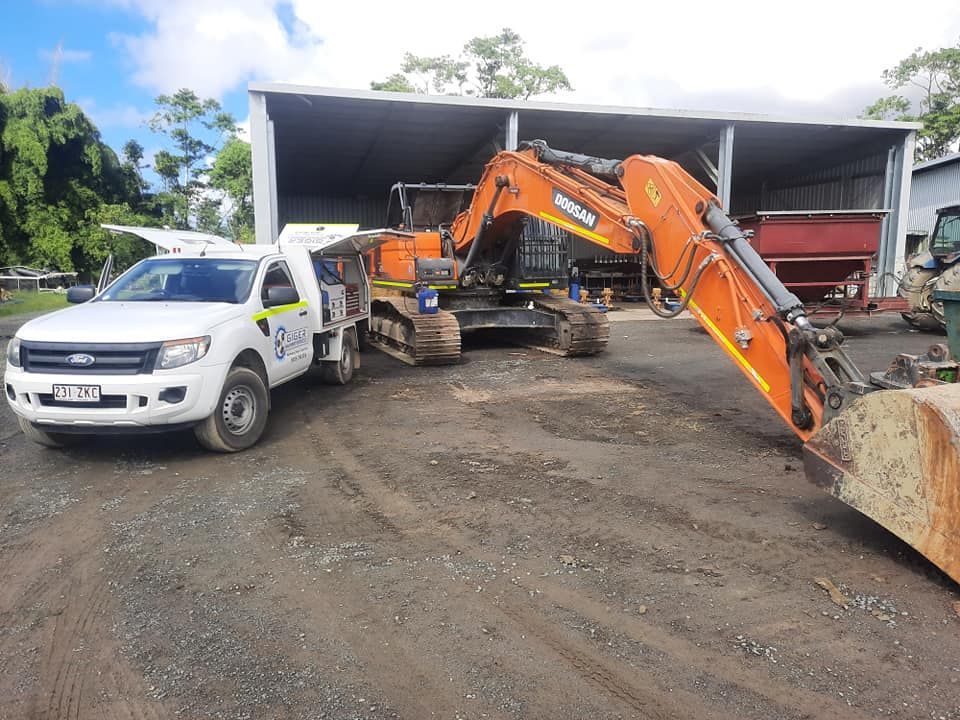 A White Truck is Parked Next to a Large Orange Excavator — Giger Machinery Services in Atherton, QLD