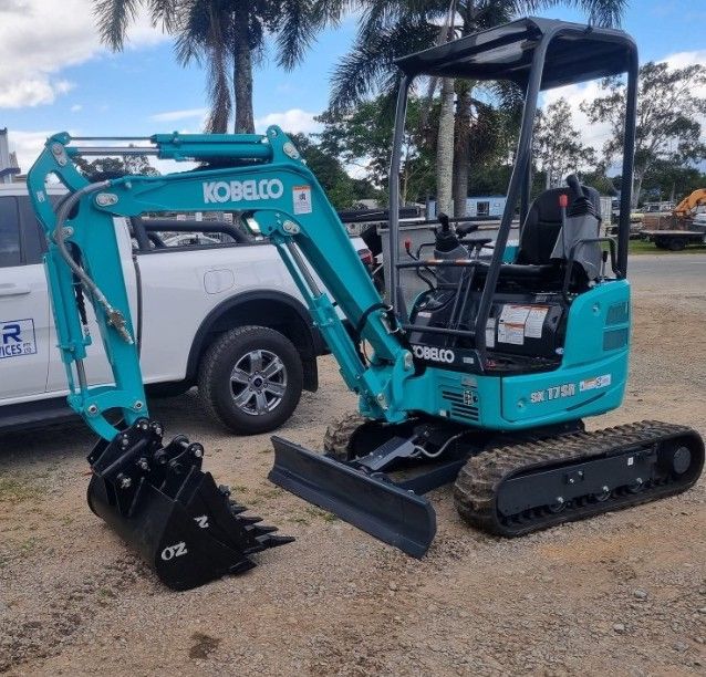 A Small Yellow Excavator Is Parked on The Side of A Gravel Road — Giger Machinery Services in Bentley Park, QLD