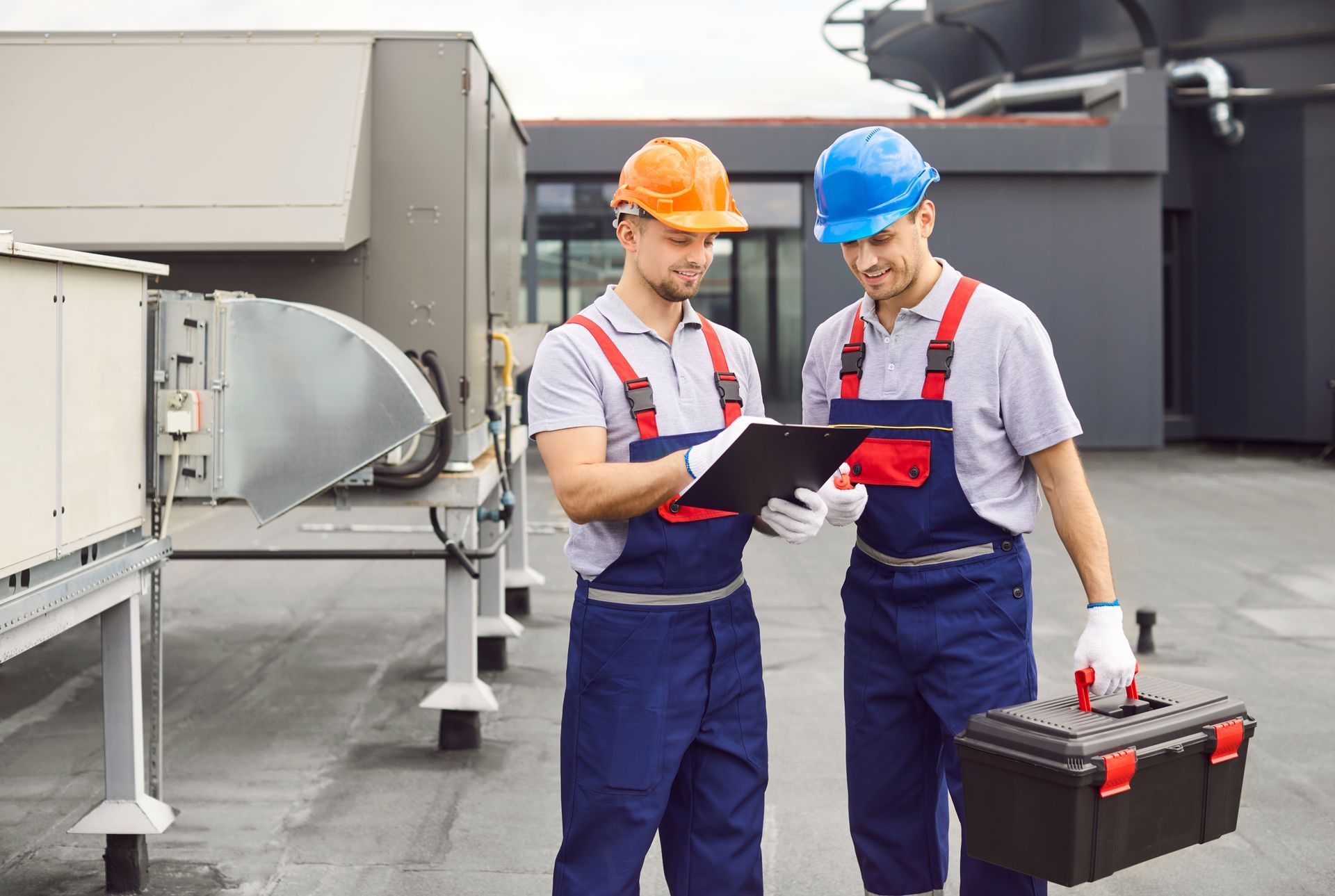 Two construction workers are standing next to each other looking at a clipboard.