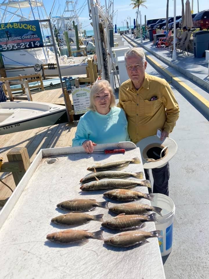 A man and a woman are standing next to a table full of fish.