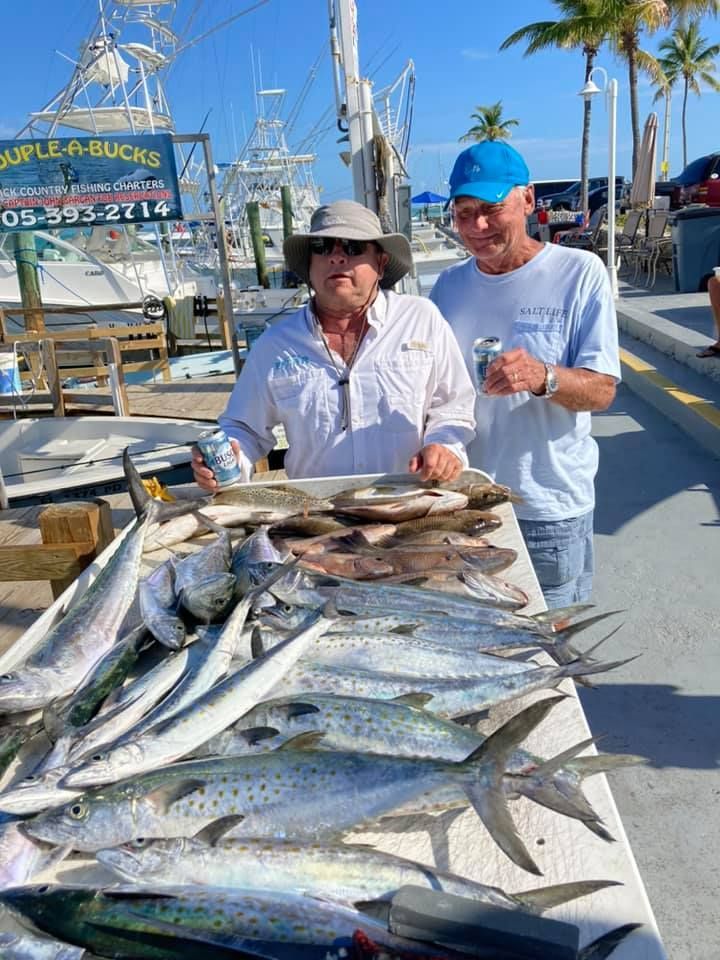 Two men are standing next to a table full of fish.