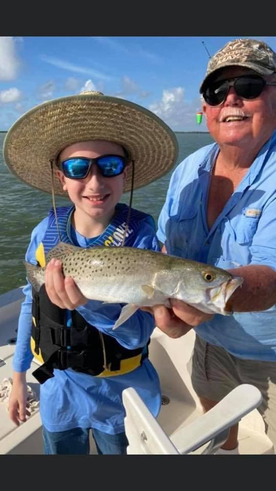 A man and a boy are holding a fish on a boat.
