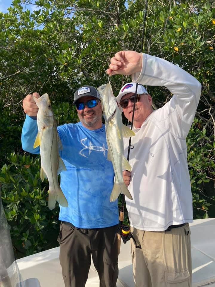 Two men are holding fish in their hands on a boat.
