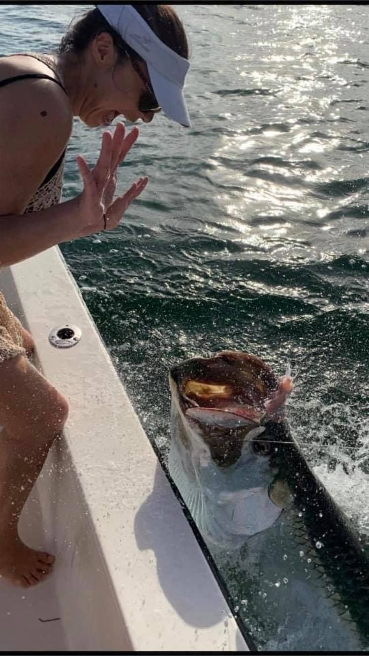 A woman is standing on a boat looking at a fish in the water.