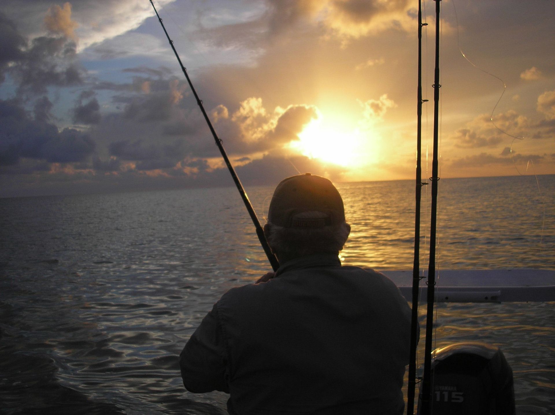 A man is fishing in the ocean at sunset