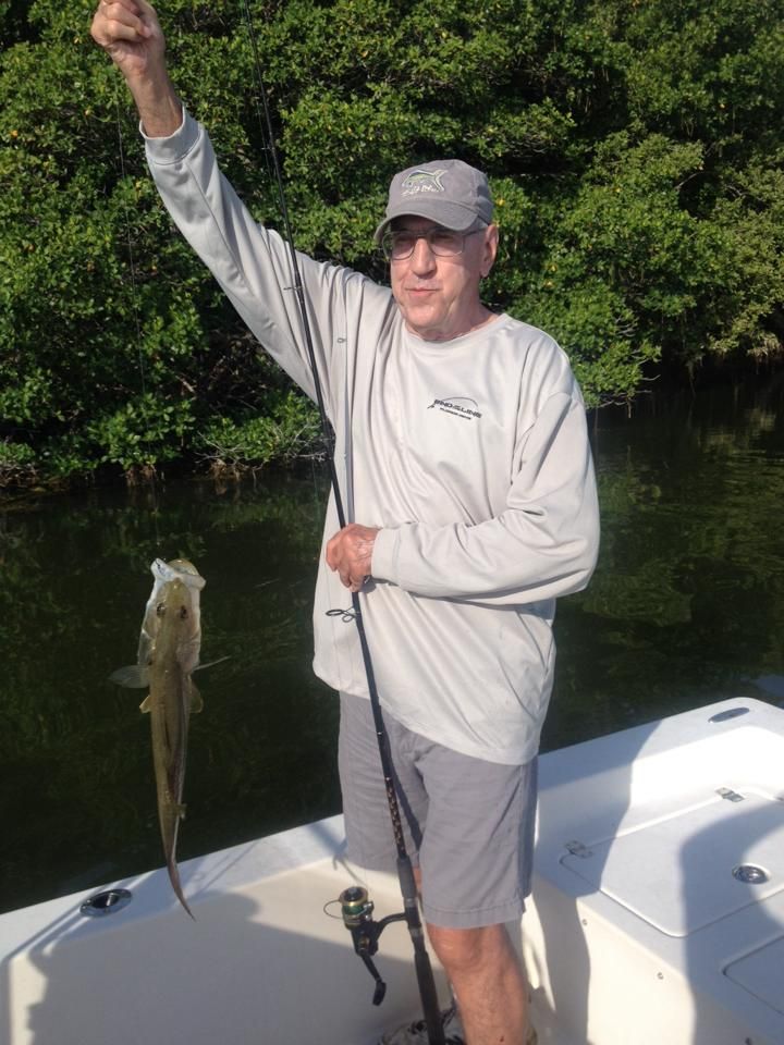 A man is standing on a boat holding a fish in his hand.