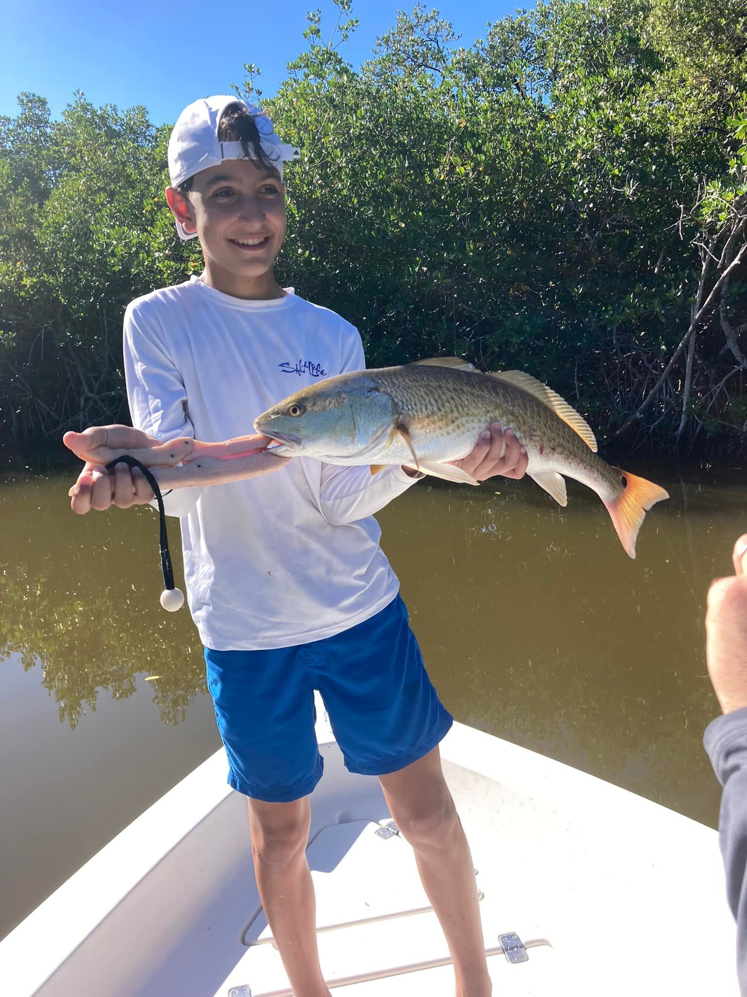 A young boy is holding a large fish on a boat.