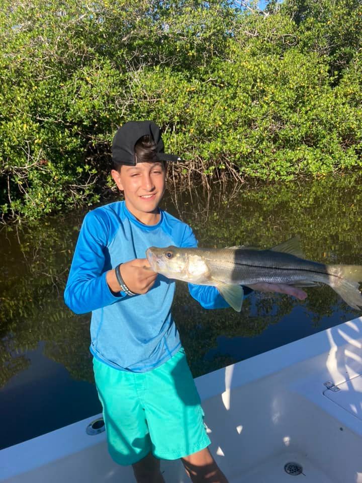 A young boy is holding a large fish on a boat.