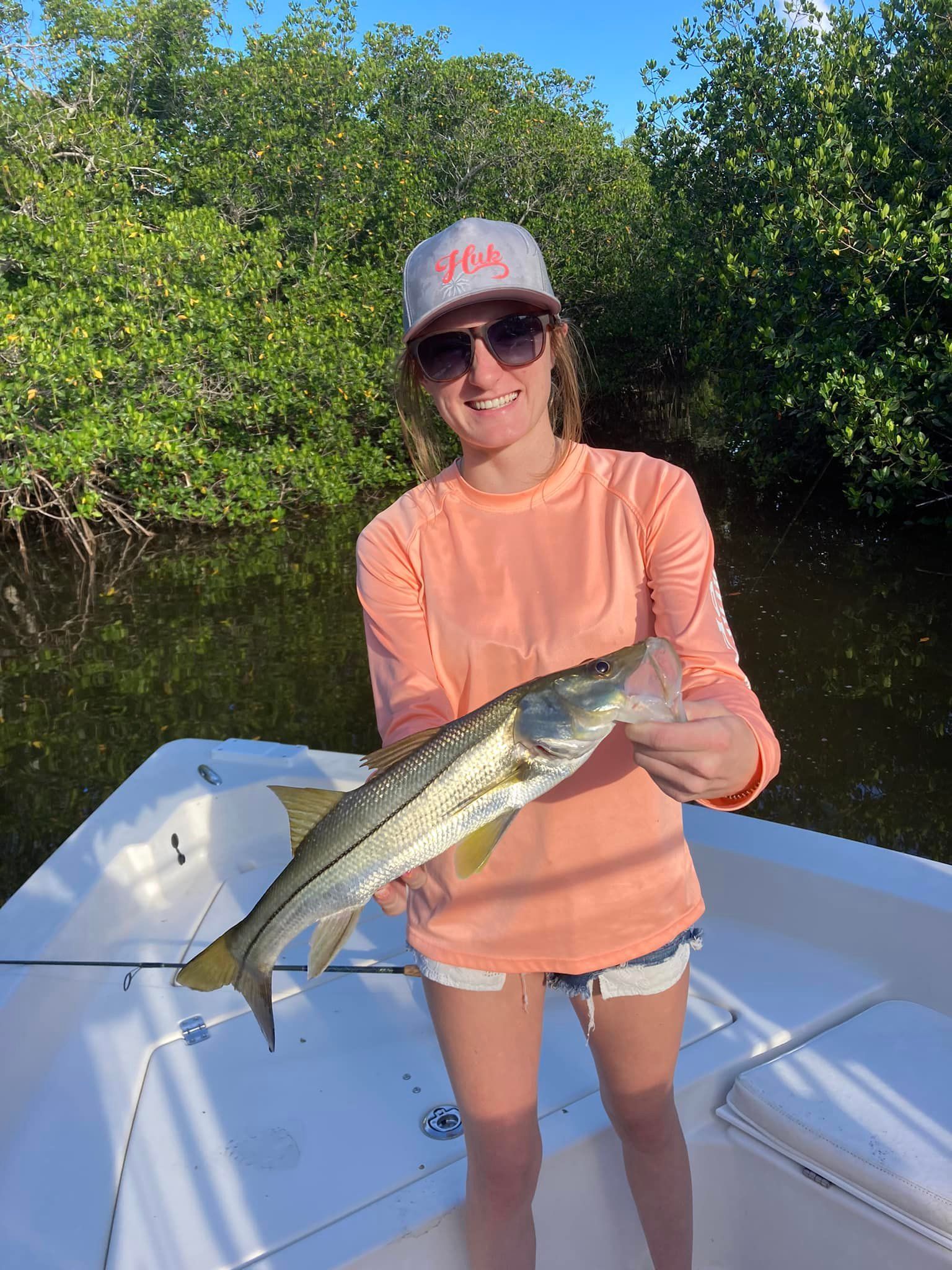A woman is holding a fish on a boat.
