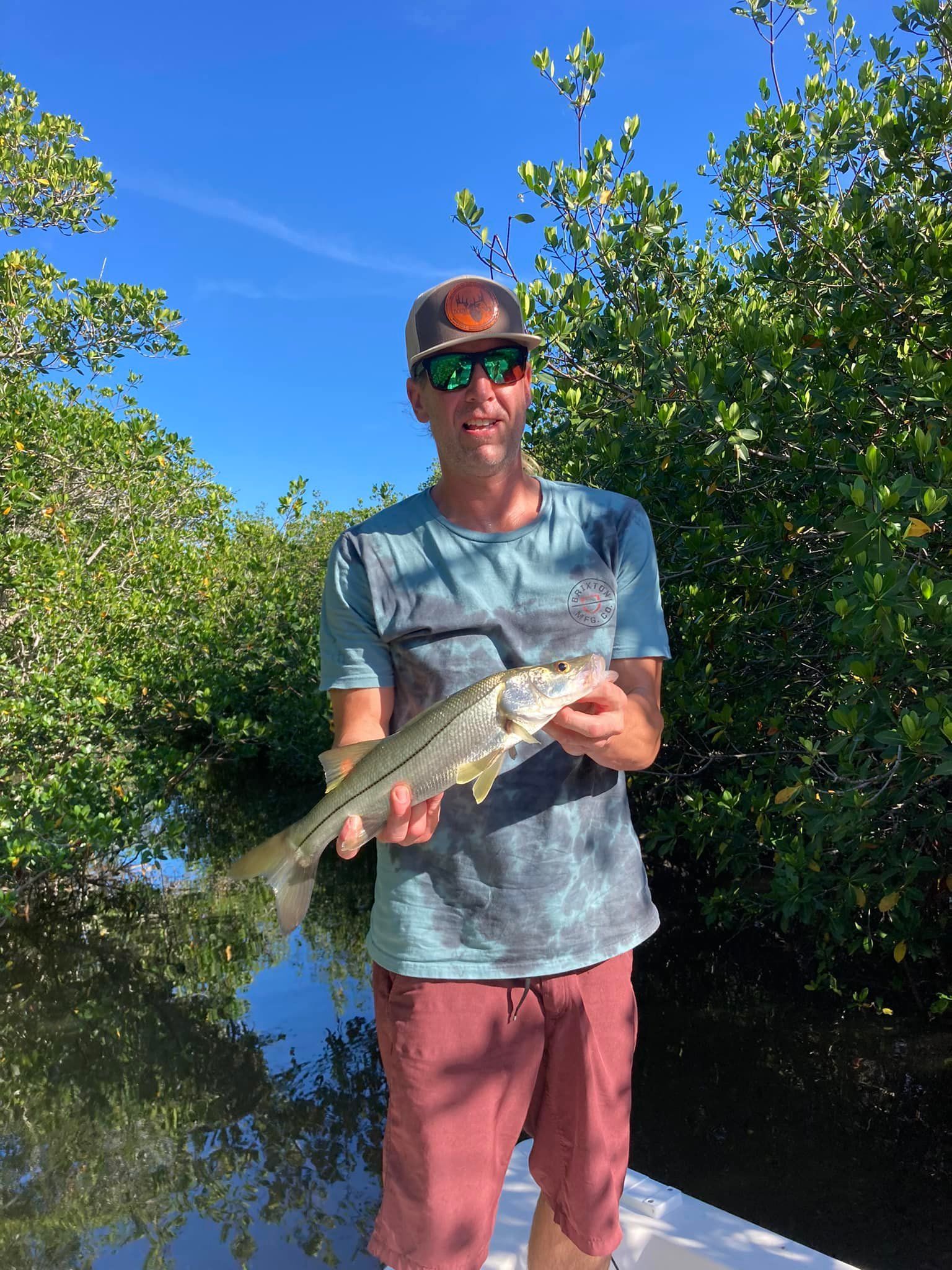 A man is standing on a boat holding a fish in his hands.