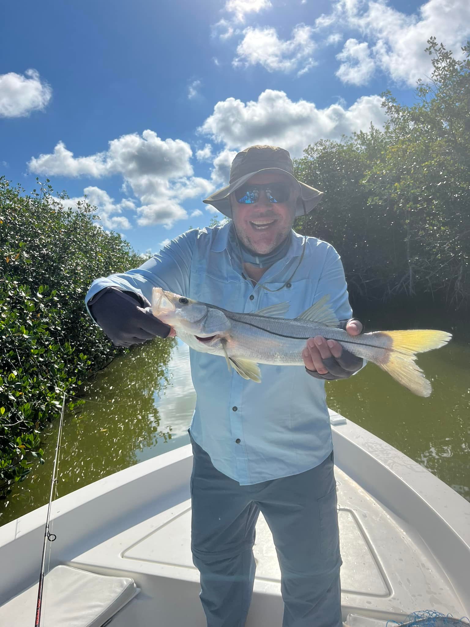 A man is standing on a boat holding a fish in his hands.