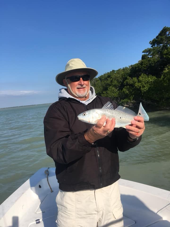 A man is standing on a boat holding a fish in his hands.