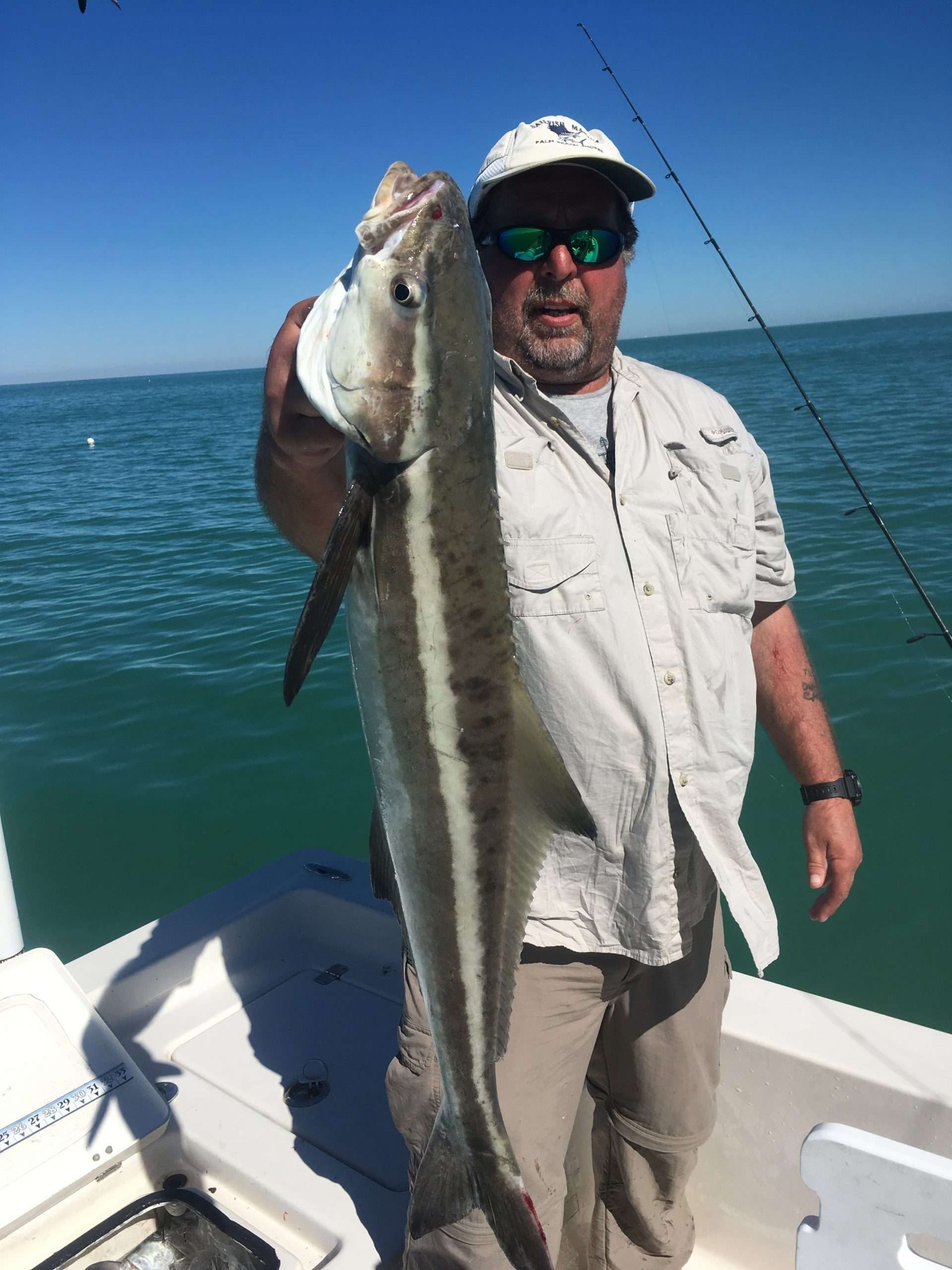 A man is holding a large fish on a boat.