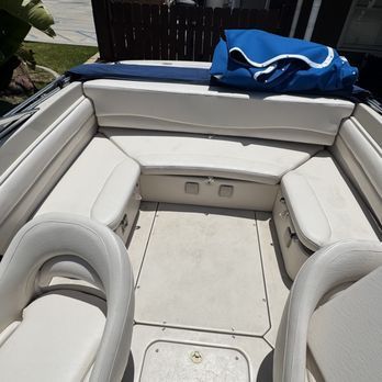 Interior of a boat with cream-colored seating. There's a back bench, side seats, and front captain's chairs, all in the same neutral color.