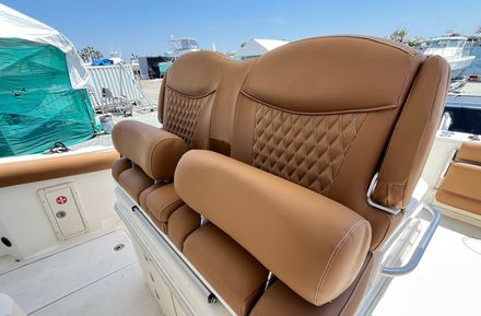 Two tan boat seats with diamond stitching and bolster cushions. The seats are in an outdoor setting on a boat. — Boat Canvas in Costa Mesa, CA
