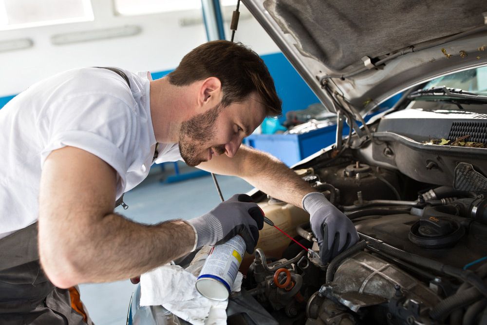 A Man Is Working On The Engine Of A Car In A Garage — Canberra AutoCare In Fisher, ACT