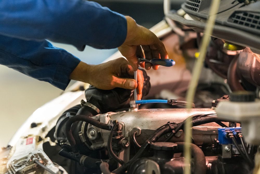 A Man is Working on a Car Engine With a Wrench — Canberra AutoCare In Fisher, ACT