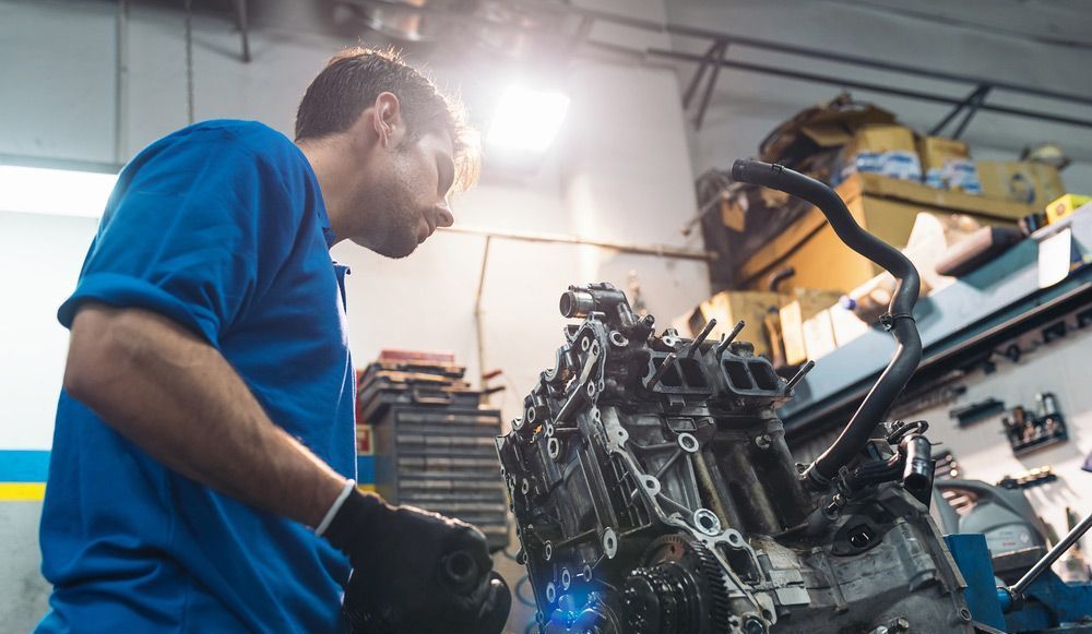 A Man Is Working On A Car Engine In A Garage — Canberra AutoCare In Fisher, ACT