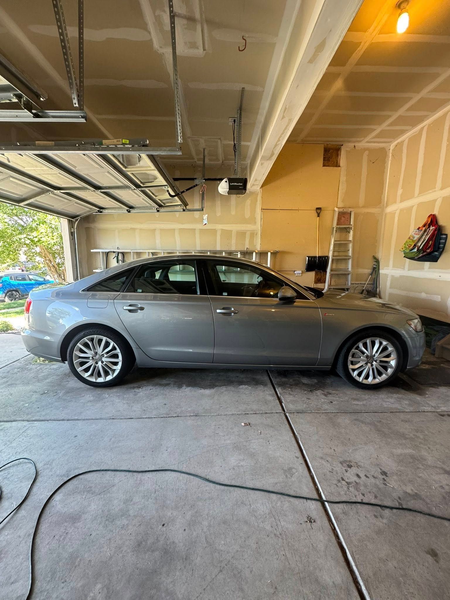 Silver sedan parked in a garage; a ladder and other items are visible.