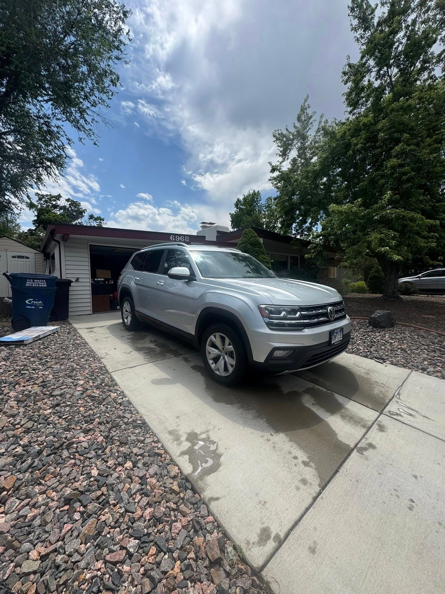 Silver SUV parked in a driveway in front of a house on a sunny day.